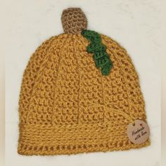 a yellow knitted hat with a green leaf on the front and brown brim