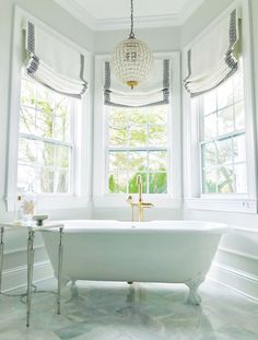 a white bath tub sitting next to two windows