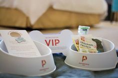 two white bowls with food in them on a table next to a bed and pillows