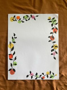 a piece of paper with an image of leaves and flowers painted on it, sitting on a bed sheet