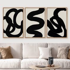 two black and white abstract paintings on the wall above a couch in a living room