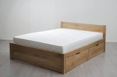 a bed with two drawers in the middle of it and a white wall behind it