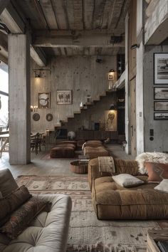 a living room filled with lots of furniture next to a stair case on the wall