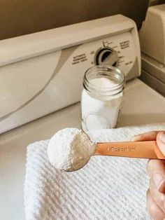 a hand holding a wooden spoon with powdered sugar on it in front of a washer