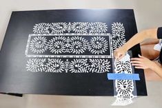 a woman is working on a table with white stencils