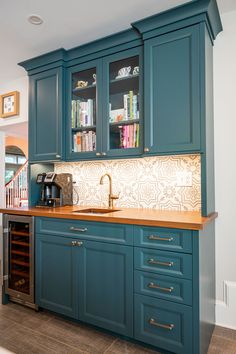 a kitchen with teal cabinets and wooden counter tops, along with a wine rack