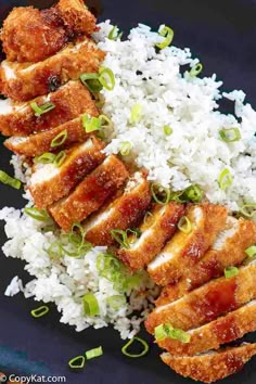 chicken and rice on a black plate with green onions