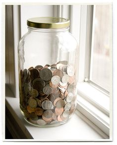 a glass jar filled with coins sitting on top of a window sill