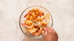 a person holding a spoon in a bowl filled with shrimp