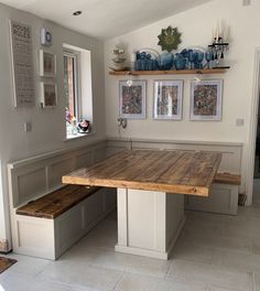 a wooden table sitting in the middle of a room with pictures on the wall above it