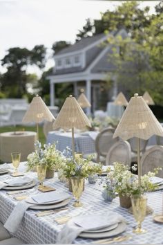 an outdoor table set with place settings and flowers in vases on the tables outside