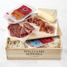 an assortment of meats and cheese in a wooden box