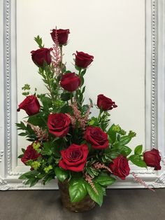 a vase filled with red roses and greenery