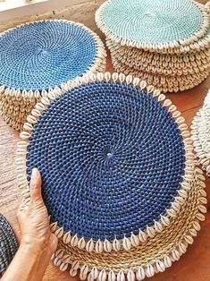 several woven baskets sitting on top of a wooden table next to a person's hand