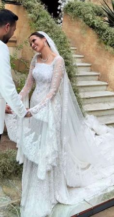 a bride and groom standing in front of some stairs