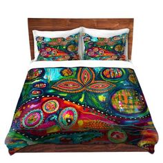 a bed covered in a colorful comforter and pillows