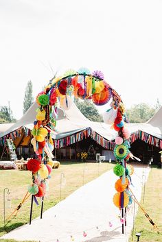 an arch decorated with colorful paper flowers and streamers for a wedding or party entrance