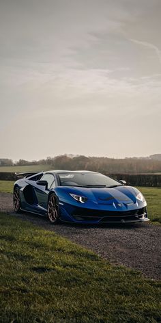 a blue sports car parked on the side of a road next to a grassy field