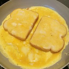 two pieces of toast sitting on top of an omelet in a frying pan