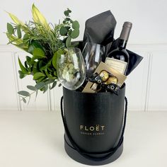 a black bucket filled with wine, chocolates and flowers