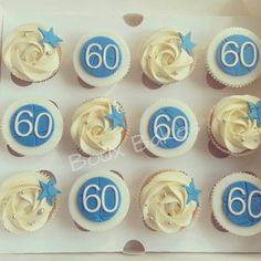 twelve cupcakes with white frosting and blue decorations