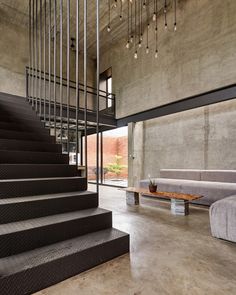 a living room with concrete walls and stairs