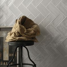 a piece of brown paper sitting on top of a black stool next to a wall