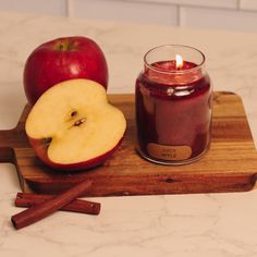 an apple and cinnamon sit on a cutting board next to a candle