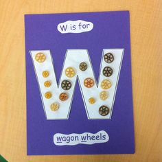 the letter w is for wagon wheels on a purple card with white and brown buttons