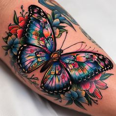 a colorful butterfly with flowers on its wings is shown in this tattoo art photo shoot