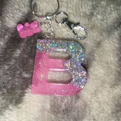 the letter e is made out of glitter and has a pink bow keychain