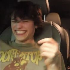 two young men sitting in the back seat of a car and one is holding a beer