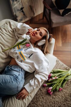 a woman laying on the floor with flowers in her hand and listening to headphones