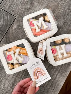 three small white boxes filled with different types of candy and candies on top of a wooden table