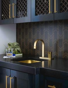 a kitchen with black cabinets and gold faucets on the countertop, next to a sink