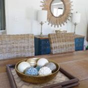 a bowl filled with balls sitting on top of a wooden table next to two wicker chairs