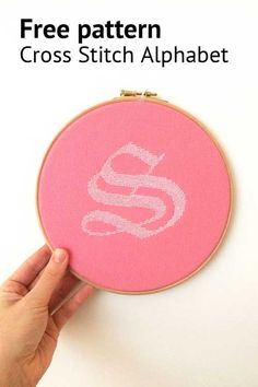 someone is holding up a pink embroidery hoop with the letter s on it