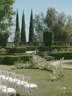 white chairs are set up in the middle of a garden