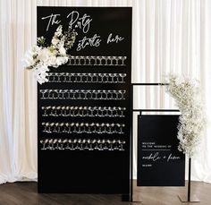 a black and white wedding sign with flowers on it next to a display for bracelets