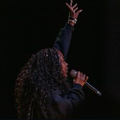 a woman with her arms up in the air while holding a microphone to her side