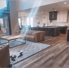 a living room filled with furniture next to a kitchen and dining room table on top of a hard wood floor