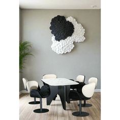 a dining room table with six chairs and a round wall decoration above it in black and white