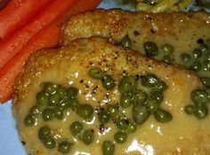 two pieces of chicken with peas and carrots on a plate