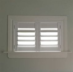 an open window with white shutters in a room