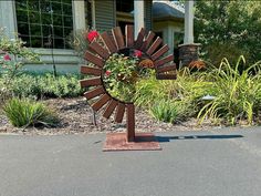 a large wooden windmill sitting in the middle of a road next to flowers and bushes