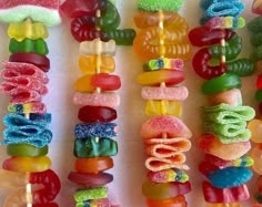 there are many colorful candy lollipops on the skewers with different toppings