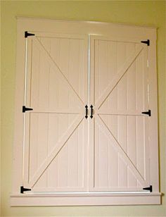 an open white barn door with black hardware on the top and bottom panel, in a room