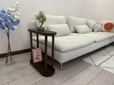 a white couch sitting next to a wooden table on top of a hard wood floor