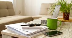 a coffee table with notebooks, pen and cell phone on it in the living room