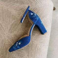 a pair of blue high heeled shoes with flowers on the heels are sitting on a chair